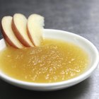 White bowl with applesauce, apples, cinnamon sticks