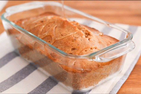 A cook pouring clear glaze over a golden-brown pound cake.