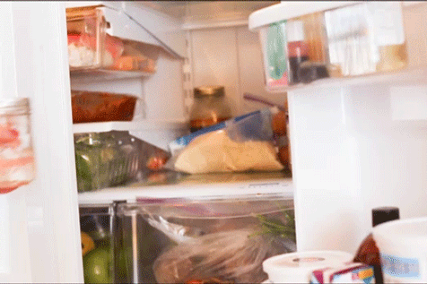 A cook placing a sealed jar of cooled glaze into a refrigerator.