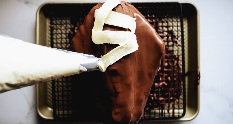 Pipe the white chocolate buttercream over the mummy to form 'buttercream bandages'.