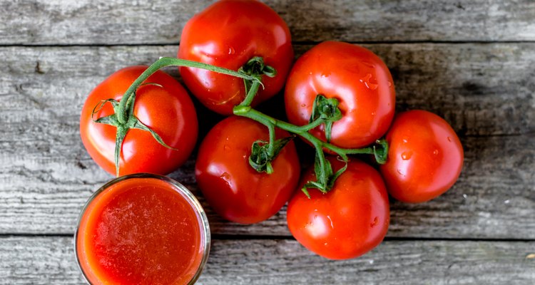 Ripe tomatoes and glass of tomato juice on wooden table