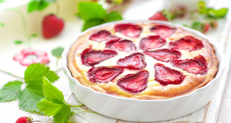 Strawberry cake in a white serving dish on a wooden surface