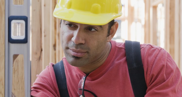 Mixed Race male construction worker using level