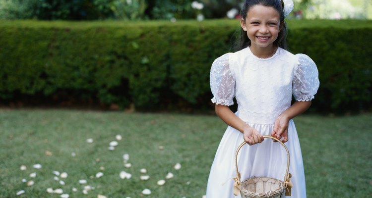 Flower girl (4-7) holding basket of petals, portrait, smiling