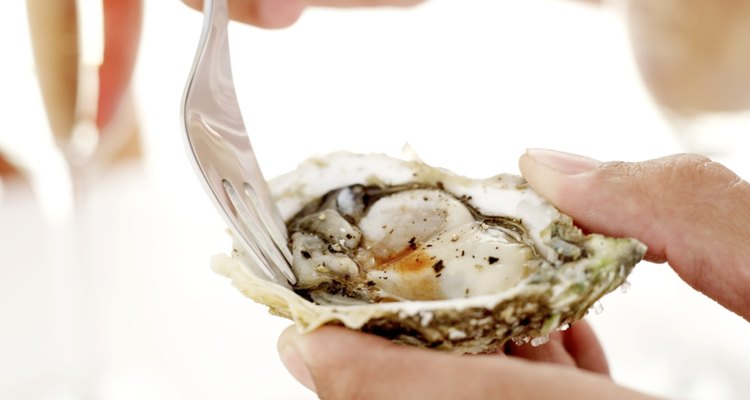 person eating an oyster from an oyster shell