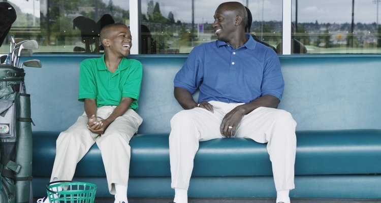 Father and son putting on golf shoes at a golf course