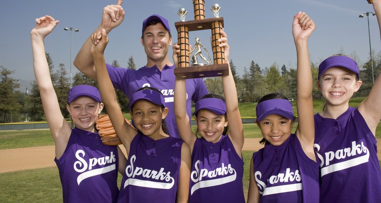 Portrait of little league softball team with coach holding trophy