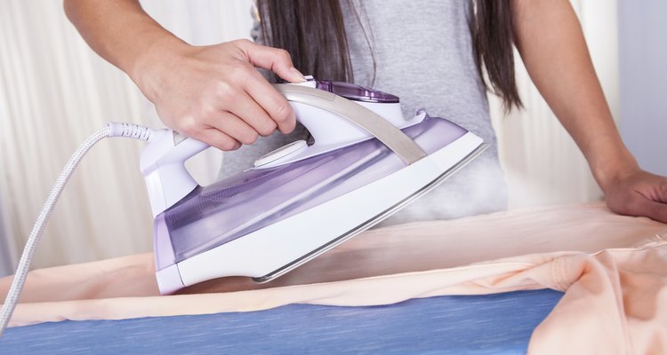 Cheerful housewife ironing the clothes
