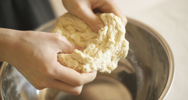 Woman making bagels, kneading dough, close up