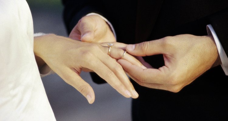 Close-up of a groom placing a ring on his bride's finger