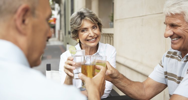 Senior woman and two senior men raising glasses, outdoors, close-up