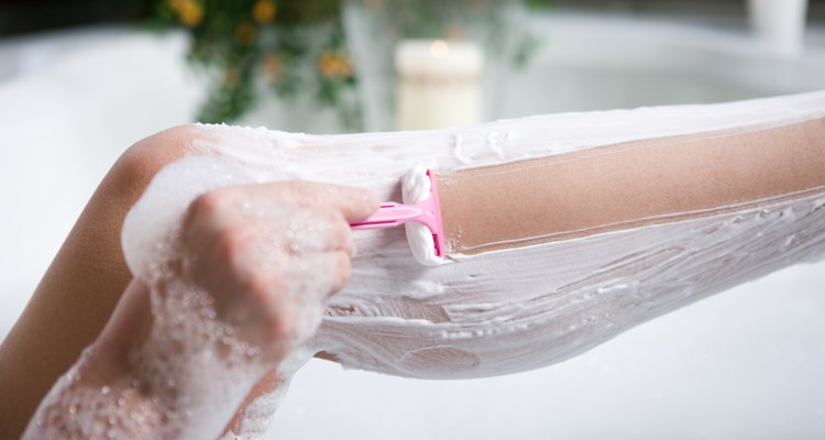 Woman shaving her legs in bathtub