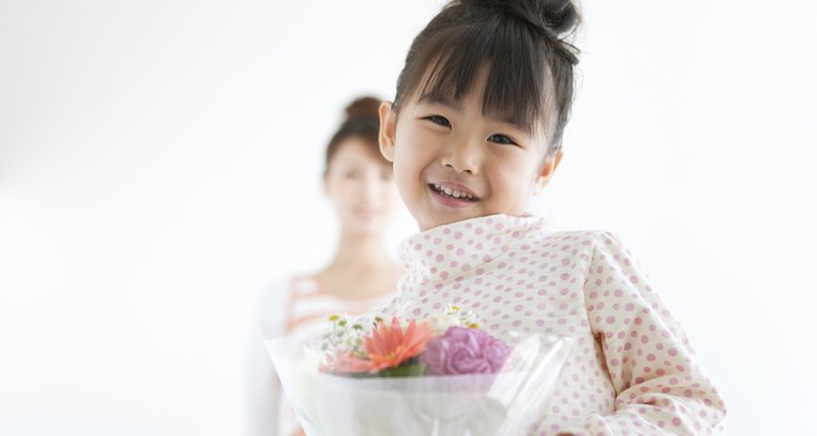 Portrait of girl with mother holding flower bouquet, white background, differential focus