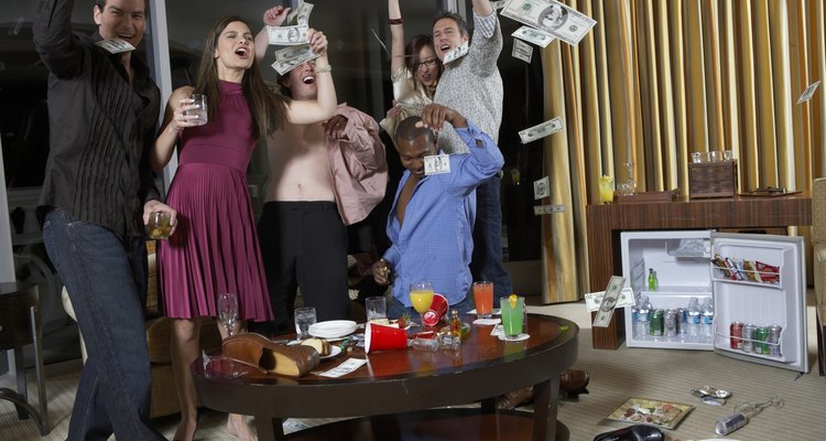 Group of people celebrating in hotel room, throwing  US dollar notes
