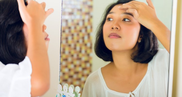 Asian woman discovering a pimple in face