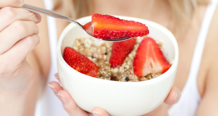 Close-up of a woman eating cereals with strawberries