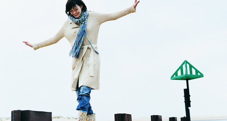 Woman Walks, Balancing With Her Arms Out on a Breakwater