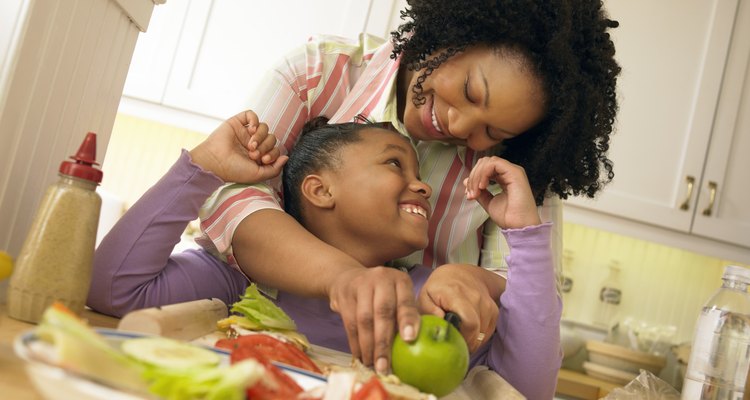 Mother Stands With Her Young Daughter in the Kitchen, Chopping an Apple for Her Lunch