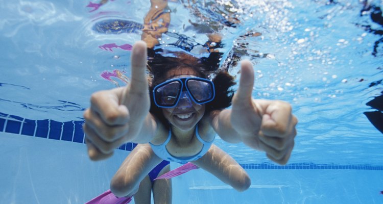 Girl (8-9) swimming underwater, showing thumbs up, underwater view