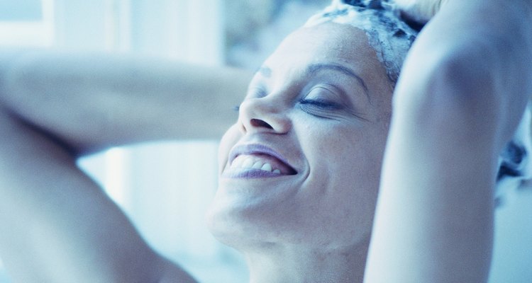 Woman shampooing hair and smiling