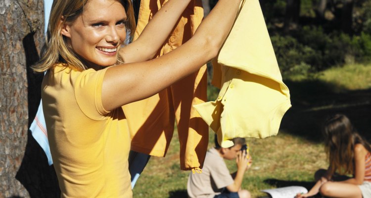 close up of mother hanging clothes on clothesline and son (8-9) and daughter (10-11) sitting on grass coloring their pictures