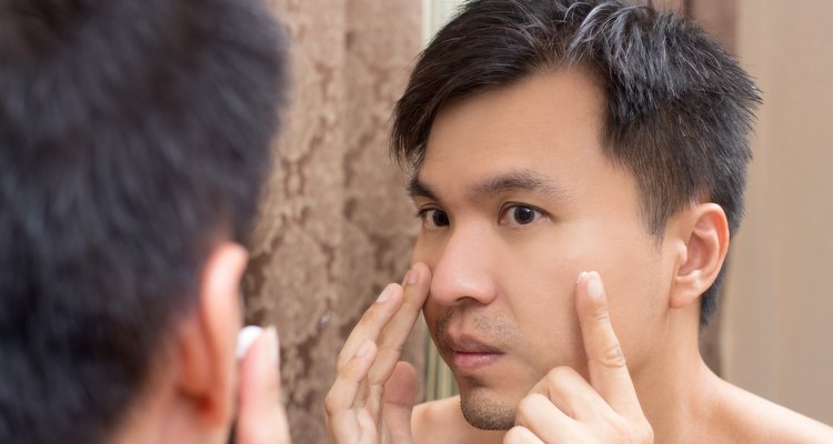 Mirror reflection of a young asian handsome man applying facial