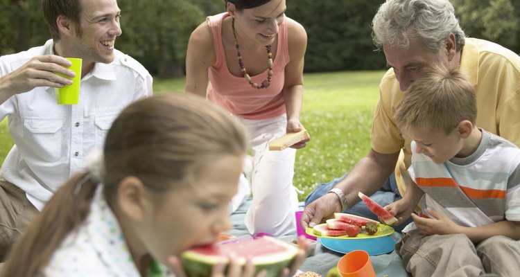 Three generational family picnicking in park, smiling