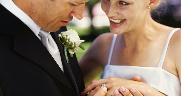 groom exchanging a ring with his bride on a lawn