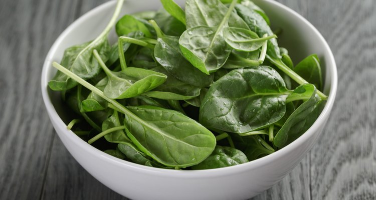 fresh spinach leaves in white bowl on wood table