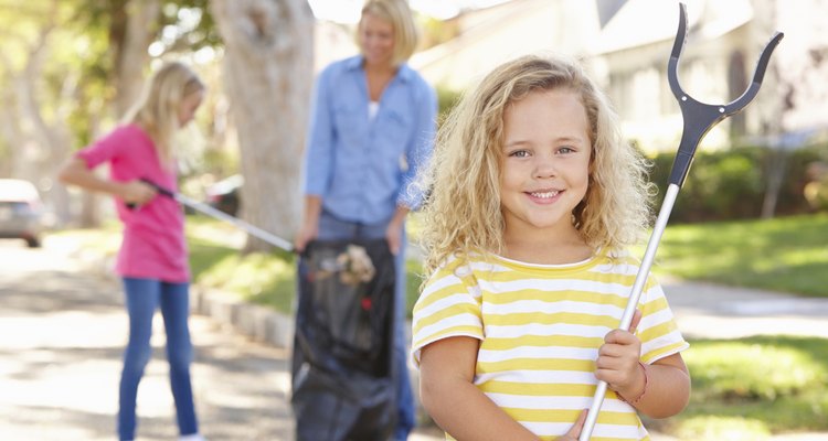 Mother And Daughters Picking Up Litter In Suburban Street