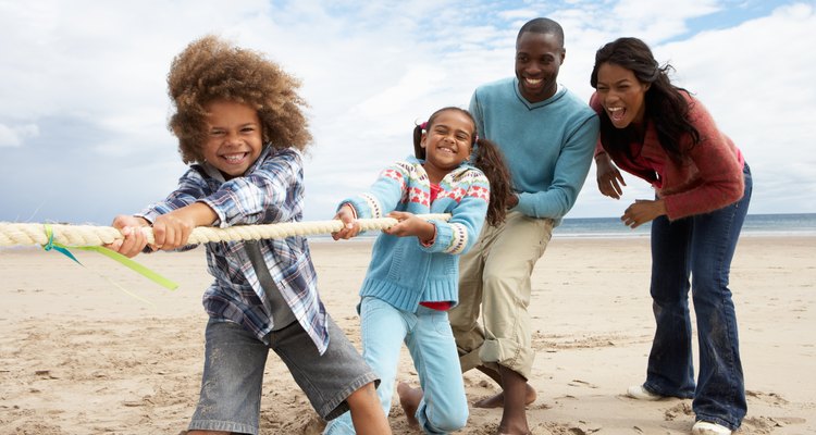 Family playing tug of war outside on a sunny day