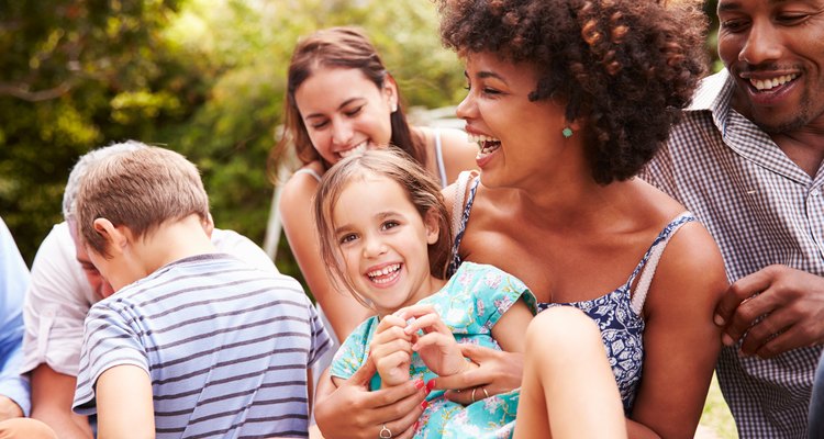Adults and kids sitting on the grass in a garden