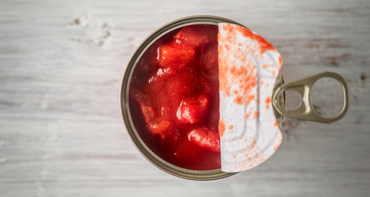 Chopped tomatoes in metal can in wooden table top view