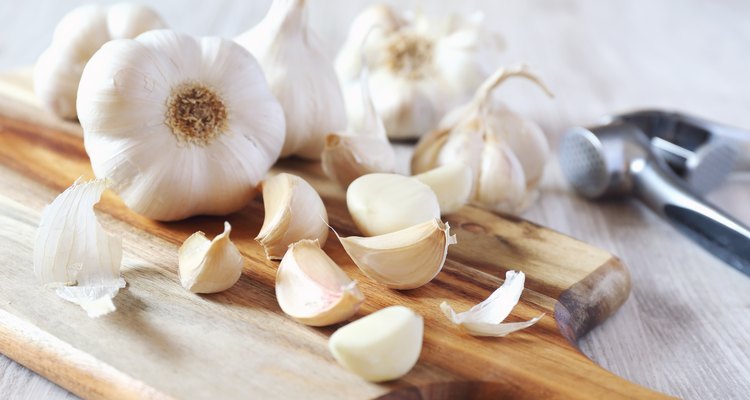 Bulbs of garlic on cutting board and garlic press