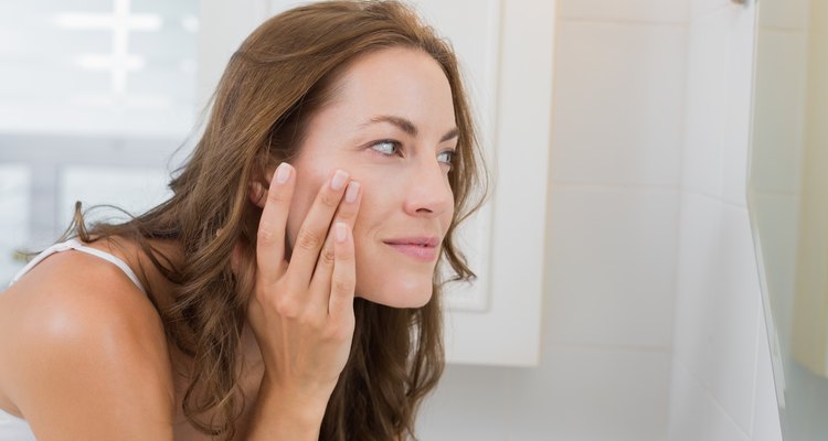Side view of a beautiful young woman examining her face